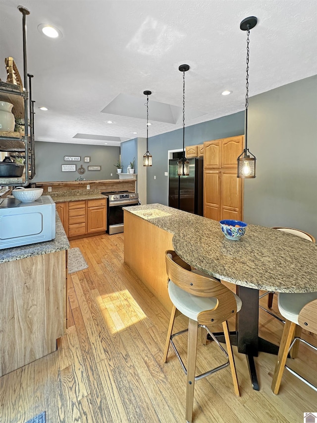 478 Lovers Ln, Benton, KY 42025 - kitchen with appliances with stainless steel finishes, light wood-style floors, a kitchen breakfast bar, light stone countertops, and recessed lighting