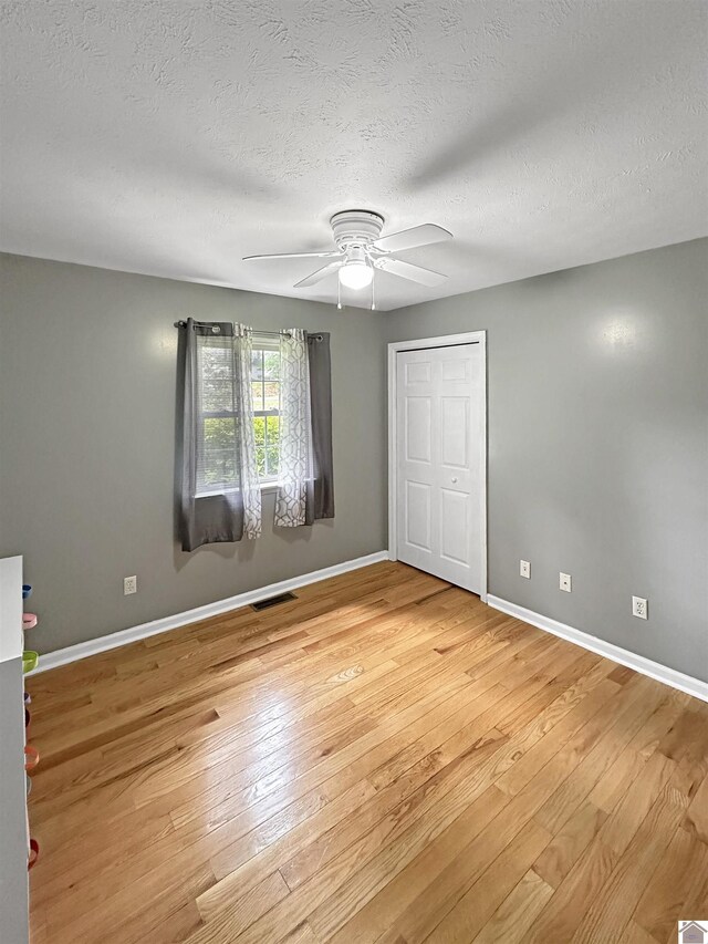 478 Lovers Ln, Benton, KY 42025 - unfurnished bedroom featuring light wood finished floors, baseboards, a textured ceiling, ceiling fan, and a closet
