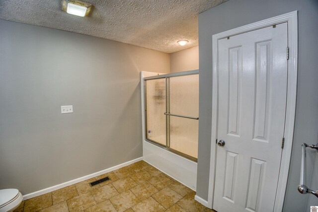 5904 Moors Camp Hwy, Gilbertsville, KY 42044 - bathroom with baseboards, enclosed tub / shower combo, toilet, a textured ceiling, and stone finish floors