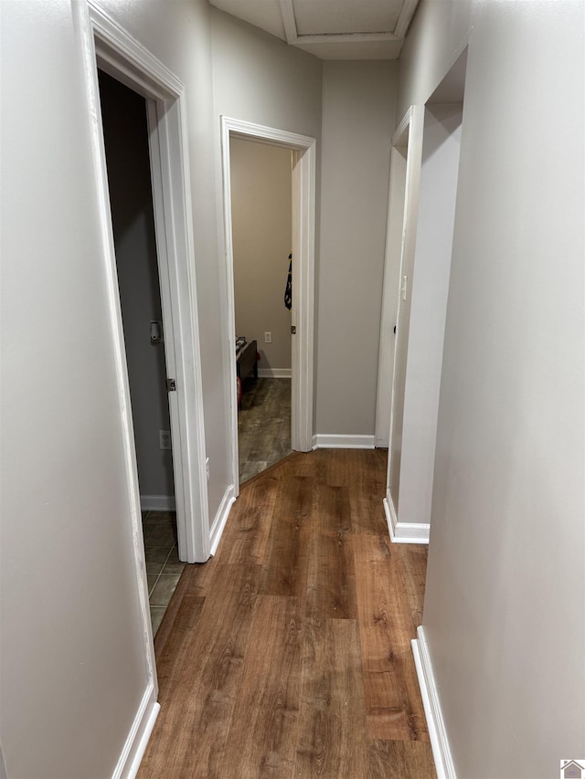 hallway with wood finished floors, attic access, and baseboards