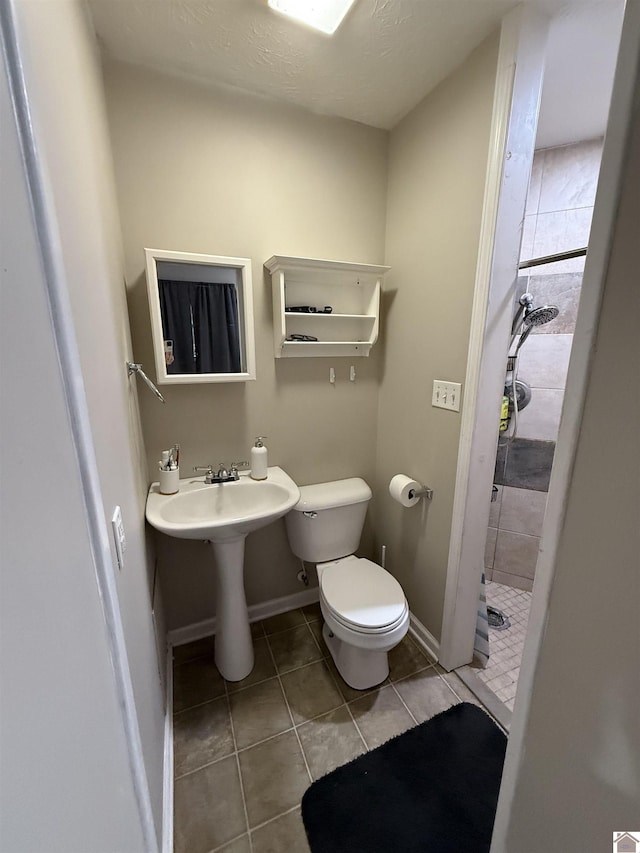 full bath with tile patterned floors, a stall shower, toilet, and baseboards