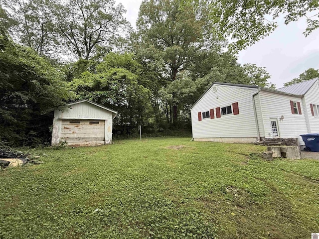 view of green lawn featuring a detached garage and an outbuilding