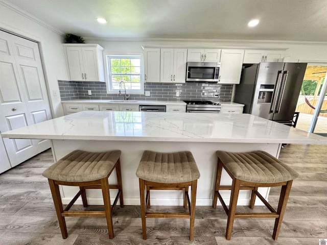 566 Golden Meadow Ln, Ledbetter, KY 42058 - kitchen with stainless steel appliances, a sink, ornamental molding, white cabinetry, and a breakfast bar area
