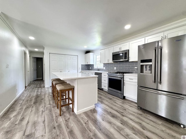 566 Golden Meadow Ln, Ledbetter, KY 42058 - kitchen featuring appliances with stainless steel finishes, crown molding, a center island, light countertops, and white cabinets