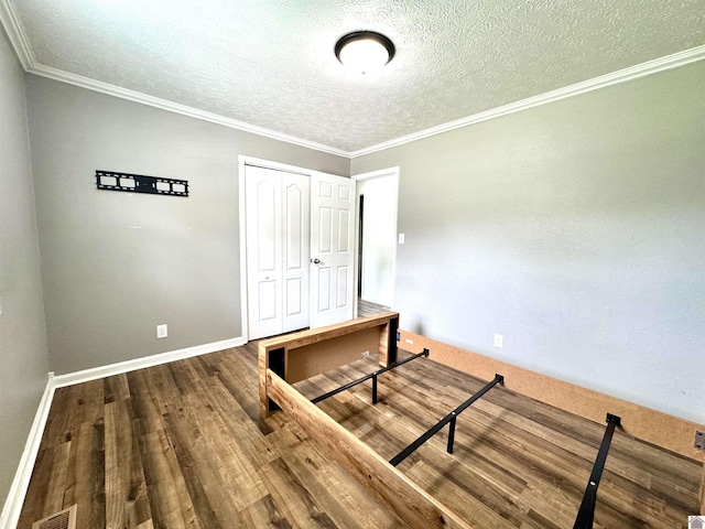 566 Golden Meadow Ln, Ledbetter, KY 42058 - unfurnished bedroom with a textured ceiling, wood finished floors, a closet, baseboards, and crown molding