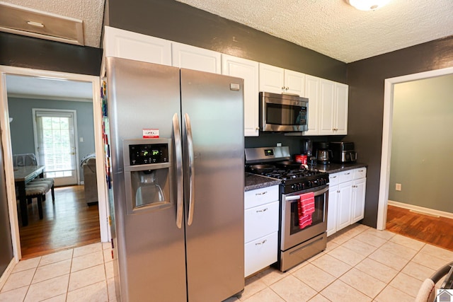 1124 Friedman Ln, Paducah, KY 42001 - kitchen with appliances with stainless steel finishes, light tile patterned floors, dark countertops, white cabinets, and a textured ceiling