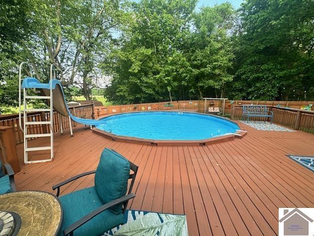 3944 Old Mayfield Rd, Paducah, KY 42003 - view of swimming pool with a water slide, a wooden deck, view of scattered trees, and fence