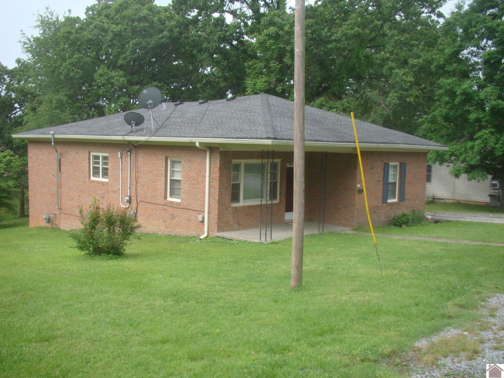 220 W Ave, Cadiz, KY 42211 - view of side of property featuring a patio, a lawn, and brick siding