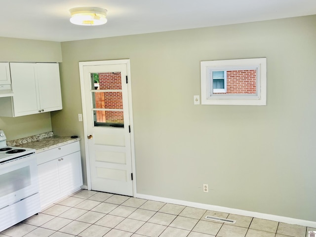 908 N 21st St, Paducah, KY 42001 - kitchen with white electric stove, light countertops, white cabinetry, light tile patterned floors, and baseboards