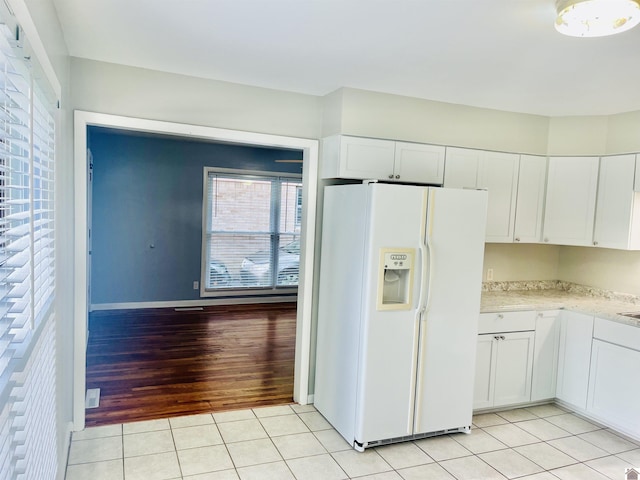 908 N 21st St, Paducah, KY 42001 - kitchen featuring white fridge with ice dispenser, light countertops, white cabinetry, light tile patterned floors, and baseboards