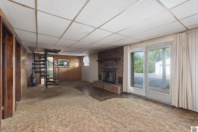 1158 State Route 295, Marion, KY 42064 - unfurnished living room with a drop ceiling, wood walls, carpet floors, stairs, and a fireplace