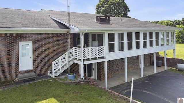 1158 State Route 295, Marion, KY 42064 - rear view of house featuring a sunroom, a shingled roof, brick siding, and a yard