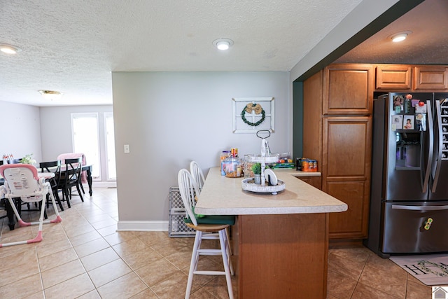 157 Calvert Dr, Paducah, KY 42003 - kitchen featuring stainless steel fridge with ice dispenser, brown cabinets, a textured ceiling, light countertops, and light tile patterned floors