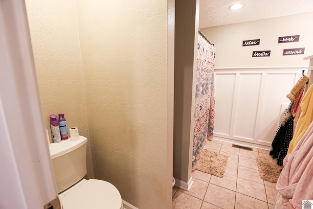 157 Calvert Dr, Paducah, KY 42003 - full bathroom featuring tile patterned floors, toilet, a shower with curtain, a wainscoted wall, and a decorative wall