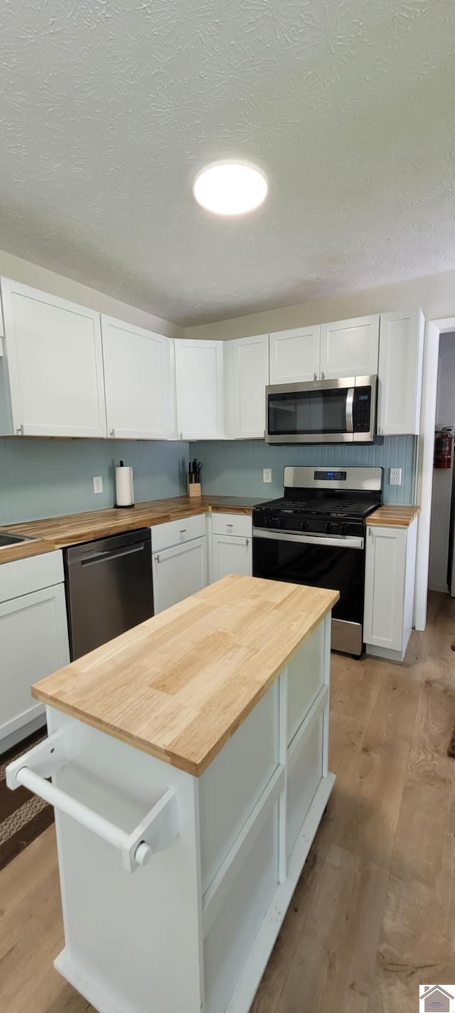 135 Phipps St, Paducah, KY 42001 - kitchen featuring wood counters, appliances with stainless steel finishes, light wood-type flooring, white cabinetry, and a textured ceiling