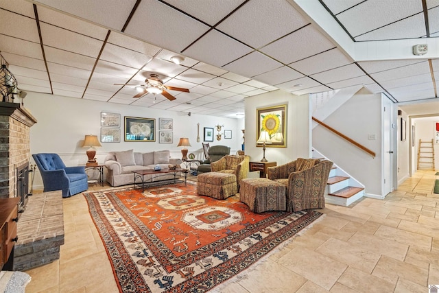 3011 Little Bear Hwy, Gilbertsville, KY 42044 - living area with stairway, a ceiling fan, a drop ceiling, a brick fireplace, and baseboards
