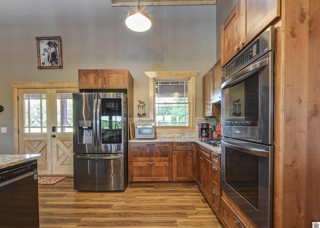3210 Douglas Rd, Murray, KY 42071 - kitchen with appliances with stainless steel finishes, a high ceiling, wood finished floors, brown cabinets, and light stone counters