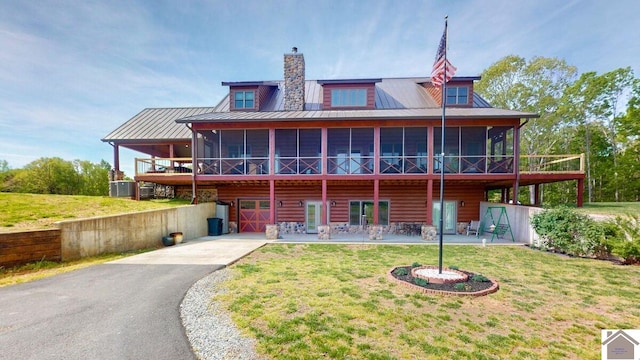 3210 Douglas Rd, Murray, KY 42071 - rear view of property with a sunroom, driveway, a lawn, a chimney, and metal roof