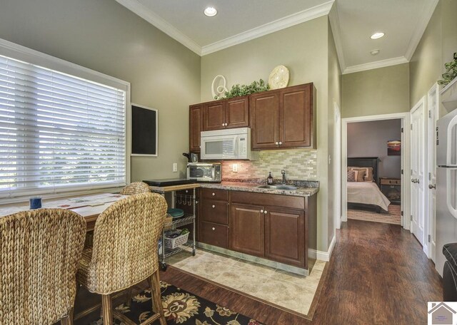 114 Shadyside Ln, Gilbertsville, KY 42044 - kitchen with white microwave, light wood finished floors, a sink, decorative backsplash, and ornamental molding