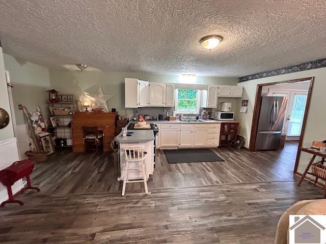 5812 State Route 123, Arlington, KY 42021 - kitchen featuring freestanding refrigerator, a textured ceiling, white cabinets, white microwave, and dark wood-style flooring