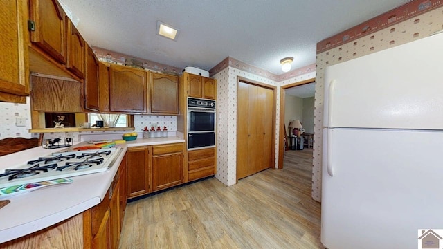199 Park St, Gilbertsville, KY 42044 - kitchen with white appliances, a warming drawer, light wood-type flooring, wallpapered walls, and light countertops
