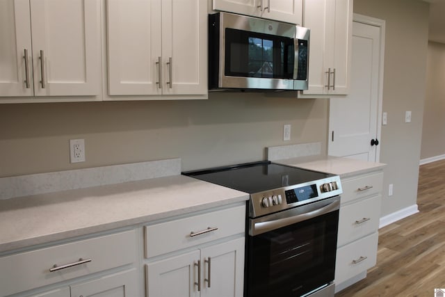 1400 Walnut St, Benton, KY 42025 - kitchen with stainless steel appliances, light wood-style floors, baseboards, and white cabinetry