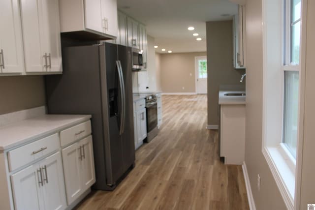 1400 Walnut St, Benton, KY 42025 - kitchen with appliances with stainless steel finishes, light wood-style flooring, a sink, white cabinetry, and recessed lighting