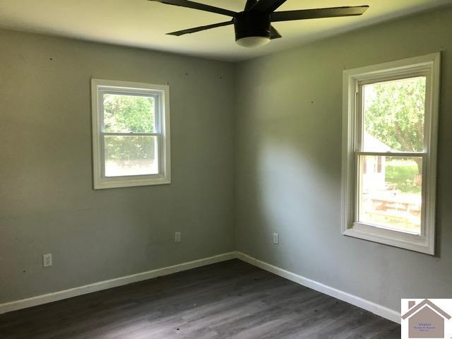 181 W 3rd St, Calvert City, KY 42029 - empty room with a ceiling fan, dark wood-type flooring, and baseboards