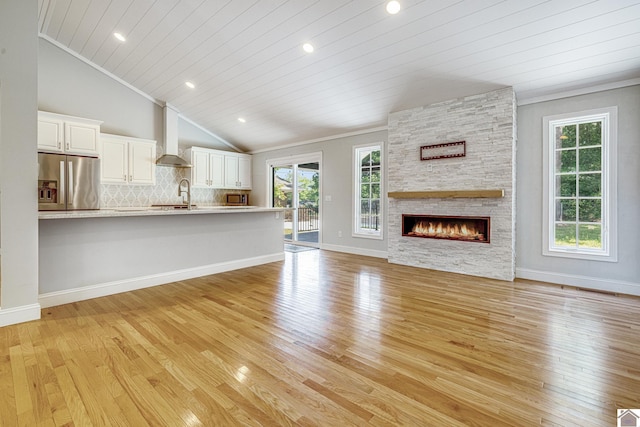 54 Grove Ln, Murray, KY 42071 - unfurnished living room featuring light wood-style flooring, healthy amount of natural light, vaulted ceiling, a sink, and a stone fireplace