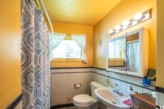 650 Cypress Cir, Calvert City, KY 42029 - bathroom featuring a sink, toilet, plenty of natural light, tile walls, and a shower with shower curtain