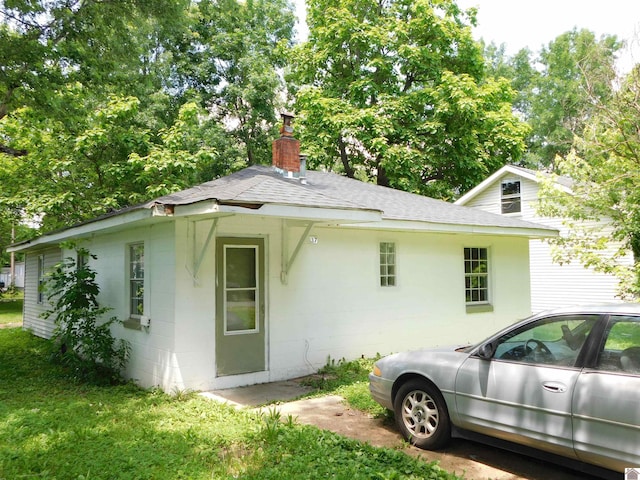 2837 Tennessee, Paducah, KY 42003 - view of home's exterior with a shingled roof, a chimney, and concrete block siding