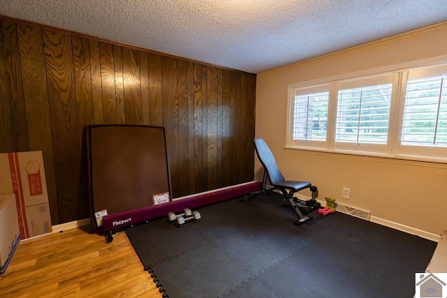 1218 Dogwood, Murray, KY 42071 - workout room with a textured ceiling, baseboards, wooden walls, and light wood-style floors