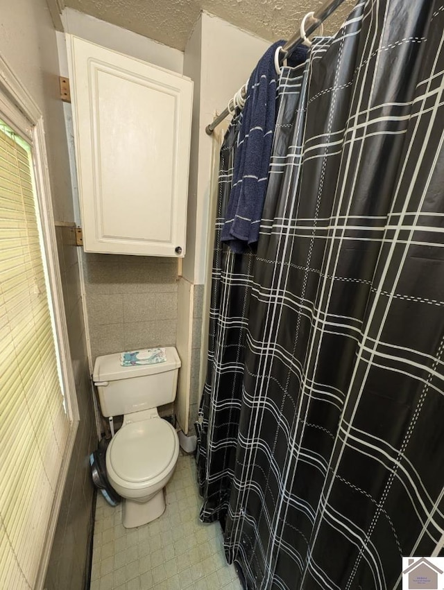 922 S 27th St, Paducah, KY 42003 - full bath featuring tile walls, toilet, a wainscoted wall, a shower with shower curtain, and a textured ceiling