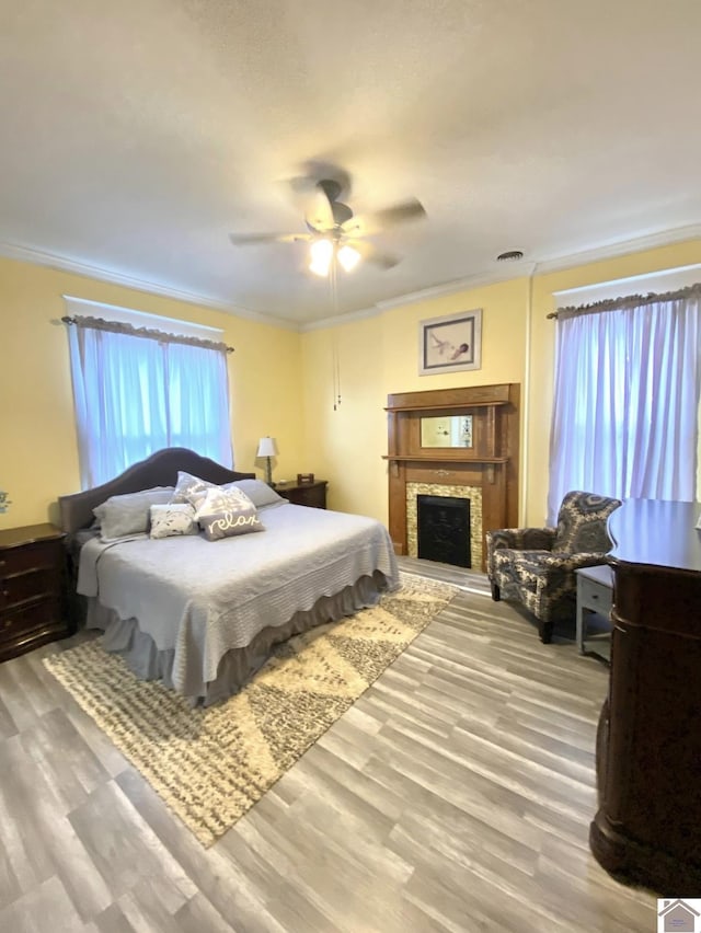 1722 Jefferson St, Paducah, KY 42001 - bedroom featuring wood finished floors, ornamental molding, a ceiling fan, and a fireplace with raised hearth