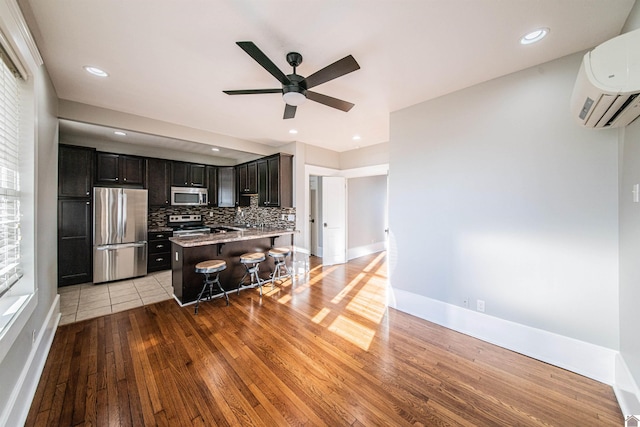 620 Madison St, Paducah, KY 42001 - kitchen featuring stainless steel appliances, a wall mounted air conditioner, a kitchen bar, light wood-style flooring, and a ceiling fan