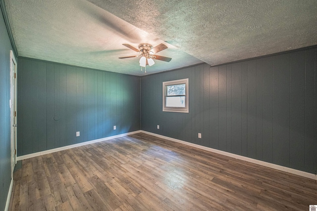 9740 Crotzer Rd, West Paducah, KY 42086 - empty room featuring a ceiling fan, wood finished floors, a textured ceiling, wooden walls, and baseboards
