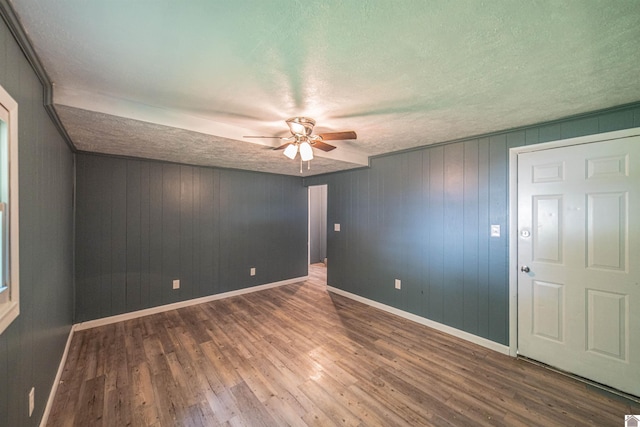 9740 Crotzer Rd, West Paducah, KY 42086 - empty room with ceiling fan, a textured ceiling, wood finished floors, baseboards, and wood walls