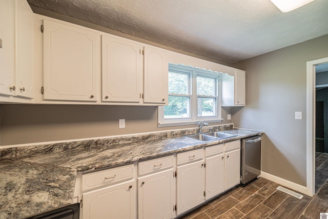 9740 Crotzer Rd, West Paducah, KY 42086 - kitchen featuring stainless steel dishwasher, a sink, white cabinets, baseboards, and a textured ceiling