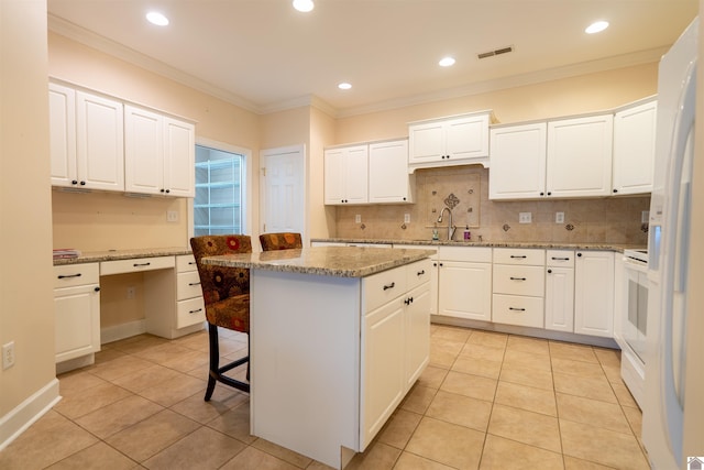 2492 Lakewood Dr, Paducah, KY 42003 - kitchen featuring a kitchen island, light tile patterned floors, backsplash, white cabinets, and crown molding