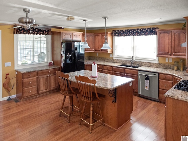 2488 Cypress Trl, New Concord, KY 42076 - kitchen with black appliances, a kitchen island, a ceiling fan, light wood-style floors, and a breakfast bar