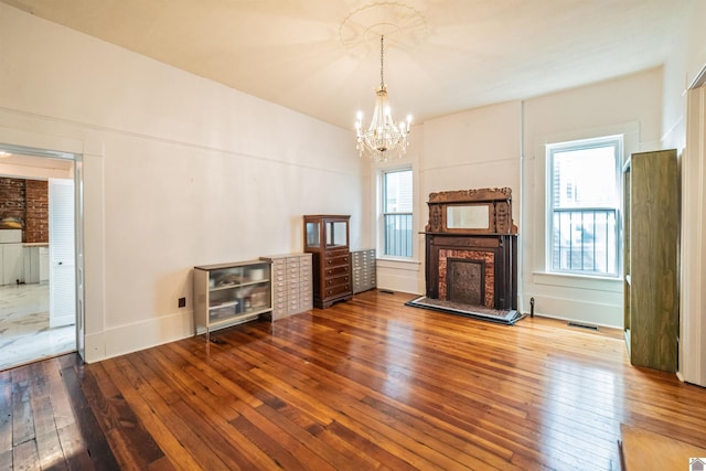 326 N 9th, Paducah, KY 42001 - unfurnished living room featuring a brick fireplace, wood-type flooring, a chandelier, and healthy amount of natural light