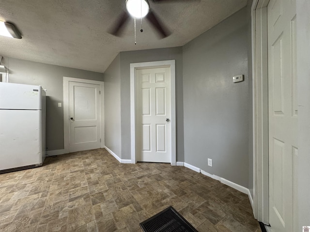67 Beshear Ln, Princeton, KY 42445 - unfurnished bedroom with freestanding refrigerator, stone finish floors, a textured ceiling, and a ceiling fan