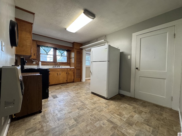 67 Beshear Ln, Princeton, KY 42445 - kitchen featuring freestanding refrigerator, brown cabinetry, black electric range, light stone finish flooring, and a textured ceiling
