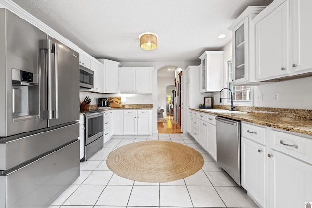 130 Camden Way, Paducah, KY 42001 - kitchen with stainless steel appliances, arched walkways, light tile patterned floors, glass insert cabinets, and white cabinets