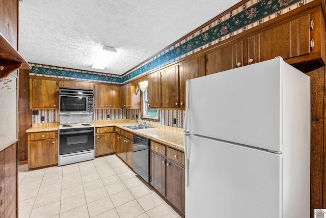 301 Tremont Dr, Hopkinsville, KY 42240 - kitchen featuring black appliances, light countertops, a textured ceiling, light tile patterned flooring, and brown cabinetry