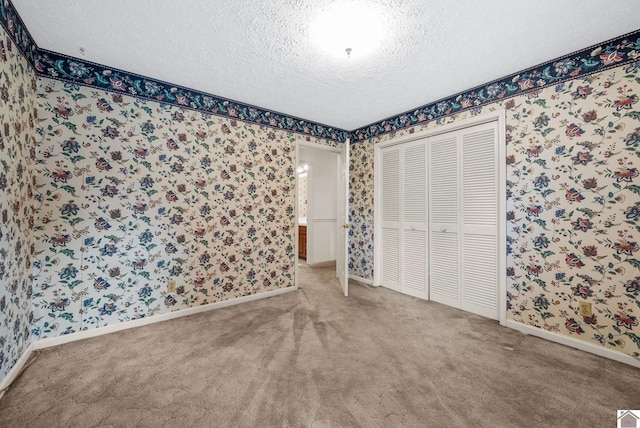 301 Tremont Dr, Hopkinsville, KY 42240 - unfurnished bedroom with wallpapered walls, a textured ceiling, carpet floors, and a closet