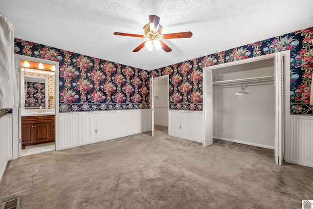 301 Tremont Dr, Hopkinsville, KY 42240 - unfurnished bedroom with wallpapered walls, wainscoting, a textured ceiling, carpet flooring, and a ceiling fan
