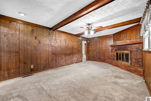 301 Tremont Dr, Hopkinsville, KY 42240 - unfurnished living room featuring wood walls, beamed ceiling, a textured ceiling, carpet floors, and a fireplace