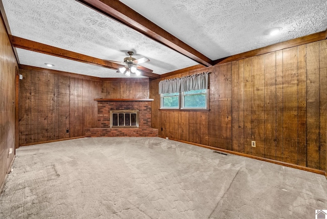 301 Tremont Dr, Hopkinsville, KY 42240 - unfurnished living room with a fireplace, wooden walls, beamed ceiling, ceiling fan, and a textured ceiling
