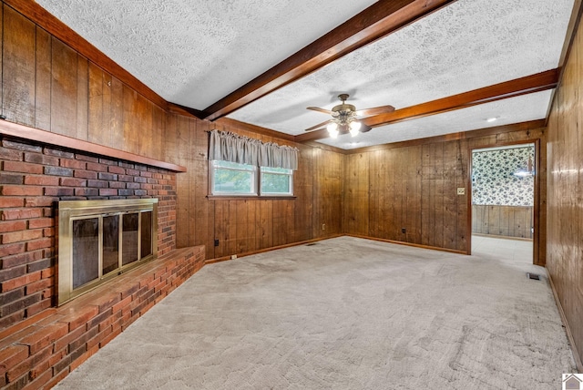 301 Tremont Dr, Hopkinsville, KY 42240 - unfurnished living room featuring wooden walls, beamed ceiling, a textured ceiling, light carpet, and a brick fireplace